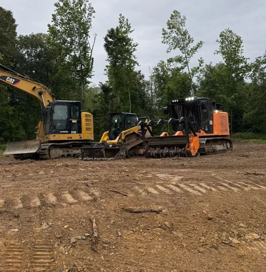CAT excavator, track loader and forestry mulcher lined up on a cleared lot